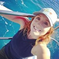 Jess Phoenix is on a boat in clear blue water, wearing a baseball hat